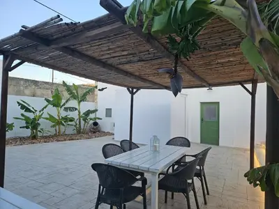 a white table and chairs under a wooden pergola at Casa Famiglia 1910 in Malona Village