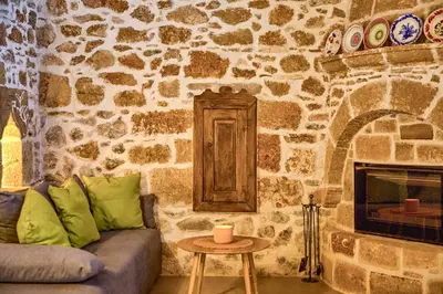 a living room with a couch and a stone wall at Casa Famiglia 1910 in Malona Village