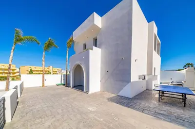 a white house with a table and palm trees at Villa Askim Evelia by Villa Plus in Ialyssos