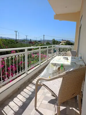a table and chairs on a balcony with flowers at kiki and cocos beach house in Theologos