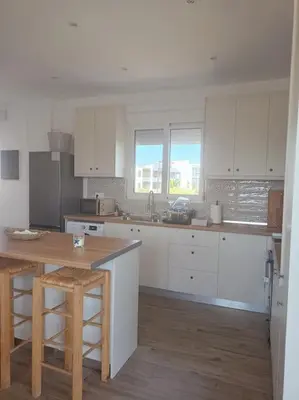 a kitchen with white cabinets and a wooden table at kiki and cocos beach house in Theologos
