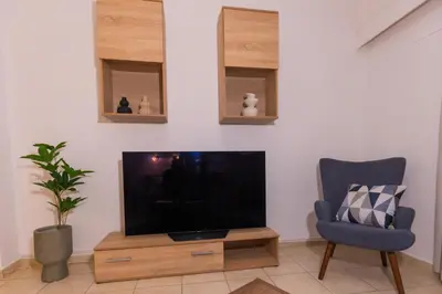 a living room with a flat screen tv and a chair at Residence City Cozy Nest in Rhodes Town