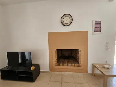 a living room with a fireplace and a clock on the wall at Villa Mare in Kiotari