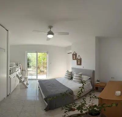 a white bedroom with a bed and a kitchen at Feraklion House in Haraki
