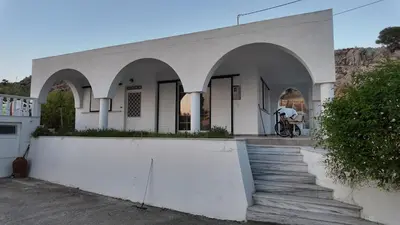 a white building with arches and a person on a bike at Feraklion House in Haraki