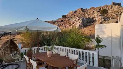 a table and chairs with an umbrella on a balcony at Feraklion House in Haraki