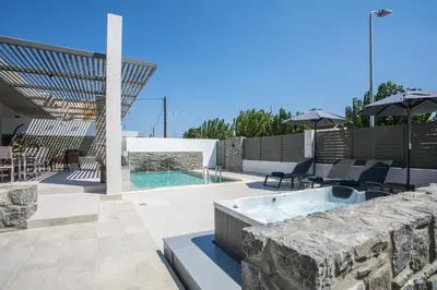 a patio with a stone wall and a swimming pool at Maro Luxury Villa in Afantou