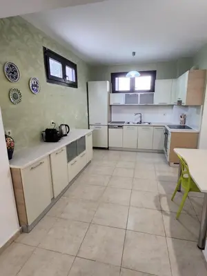 a kitchen with white cabinets and a tile floor at Grande casa di Ialysos in Ixia