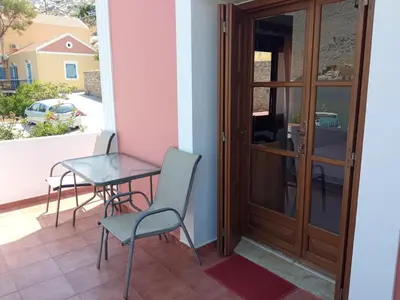 a balcony with a table and chairs and a door at Pedi Breeze in Symi