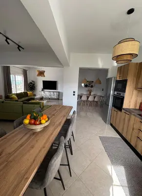 a kitchen and living room with a wooden table and chairs at Jojo's Home in Kamiros