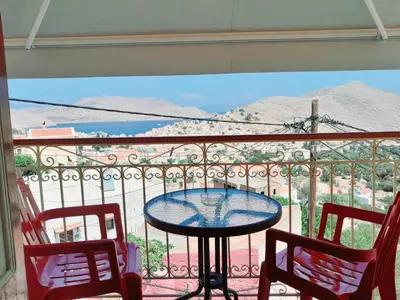 a table and two chairs on a balcony with a view at Sevasti Symi Studios in Symi