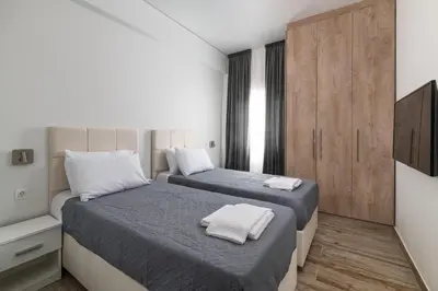 two beds in a room with white walls and wooden cabinets at Sun Dream Apartment in Rhodes Town