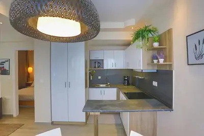 a kitchen with white cabinets and a large chandelier at Modern near the sea-Sunset View Apartments in Ixia