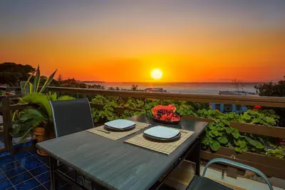 a table on a balcony with a view of the ocean at Sea View-Sunset View Apartments in Ixia