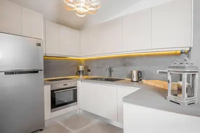 a white kitchen with white cabinets and a refrigerator at Sea View-Sunset View Apartments in Ixia