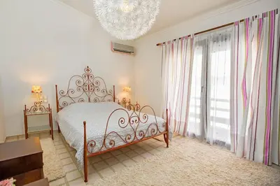 a white bedroom with a bed and a chandelier at Sea View-Sunset View Apartments in Ixia