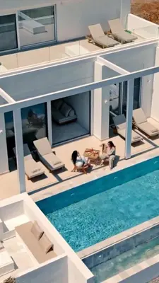 two people sitting on a house with a swimming pool at Seadream - Luxury Villa - Pool & Sea View in Lachania