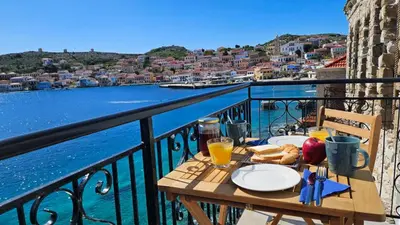 a table on a balcony with a view of the water at Ariadne in Halki