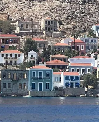 a group of houses on the shore of the water at Ariadne in Halki