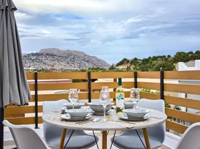 a table with chairs and wine bottles on a balcony at VaStekaHouse in Haraki