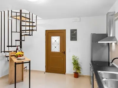 a kitchen with a wooden door and a spiral staircase at VaStekaHouse in Haraki