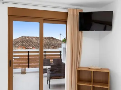 a living room with a television and a sliding glass door at VaStekaHouse in Haraki