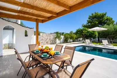 a patio with a table and chairs next to a pool at Villa Costazia in Kalithies