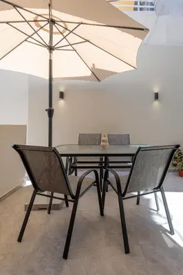 a black table with two chairs and an umbrella at Micasa Suite Rhodos in Rhodes Town
