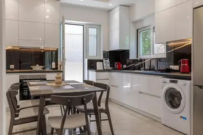 a kitchen with a table and chairs and a washer at Micasa Suite Rhodos in Rhodes Town