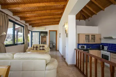 a living room with two white couches and a kitchen at Villa Pebble in Pefki Rhodes