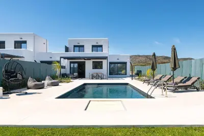 a villa with a swimming pool in front of a house at Elixir Vacation Houses in Gennadi