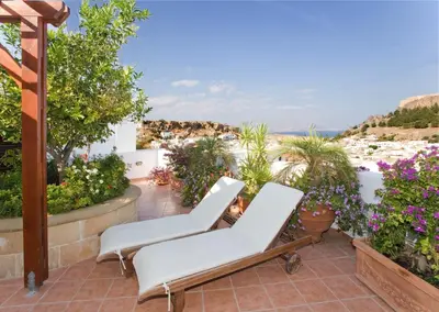 a patio with two lounge chairs and a view of the ocean at Anastasia Studios Lindos in Líndos
