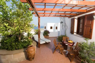 an outdoor patio with a pergola and chairs and tables at Anastasia Studios Lindos in Líndos