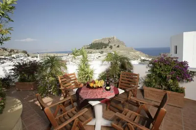 a patio with a table and chairs and the ocean at Anastasia Studios Lindos in Líndos