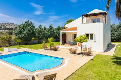 a villa with a swimming pool in front of a house at Villa Athena Classico in Kolimbia