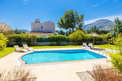 a swimming pool in a yard with chairs and a house at Villa Athena Classico in Kolimbia