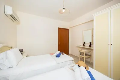 a hotel room with two beds and a chair at Villa Athena Classico in Kolimbia