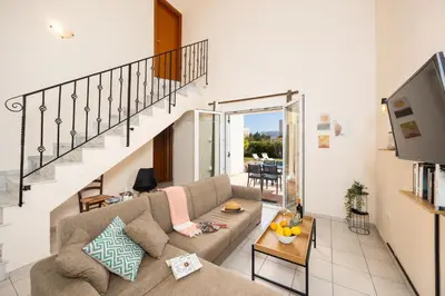 a living room with a couch and a staircase at Villa Athena Classico in Kolimbia