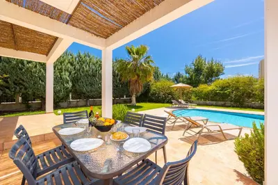 a patio with a table and chairs next to a swimming pool at Villa Apollo Classico in Kolimbia