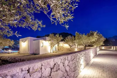 a stone wall in front of a house at night at Villa Kalathos Dream Galazio in Kalathos