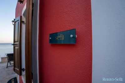 a sign on the side of a red wall at Remvi Seaside Houses in Halki