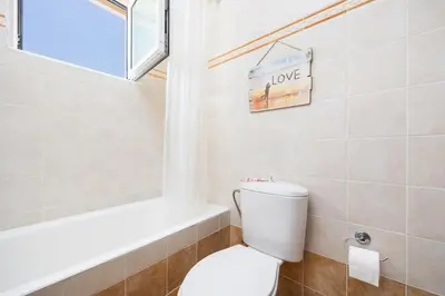 a bathroom with a toilet and a window and a tub at Villa Maia in Phanaes