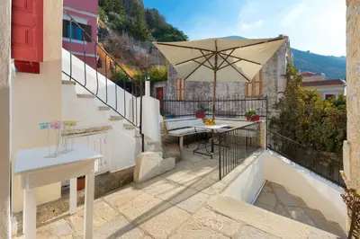 a balcony with a table and an umbrella at Castello Venetsiana in Symi