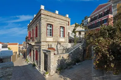 an old stone building with red shutters on a street at Castello Venetsiana in Symi