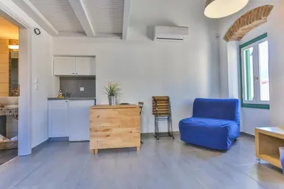 a living room with a blue chair and a kitchen at Annika Deluxe Apartments in Symi