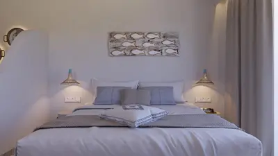 a bedroom with a large white bed with blue pillows at 'Lindian Myth' Sea View Studios in Líndos