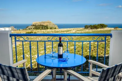a table with a bottle of wine on a balcony at 'Lindian Myth' Sea View Studios in Líndos