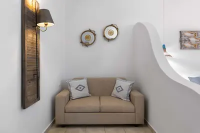 a living room with a couch and a clock on the wall at 'Lindian Myth' Sea View Studios in Líndos