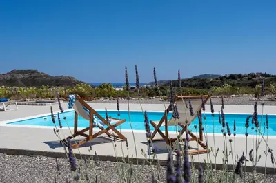 two chairs sitting next to a swimming pool at Andrealexia Sea View Villa in Kalithies