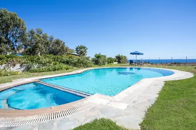 a swimming pool with chairs and the ocean in the background at Villa Seashell in Pefki Rhodes